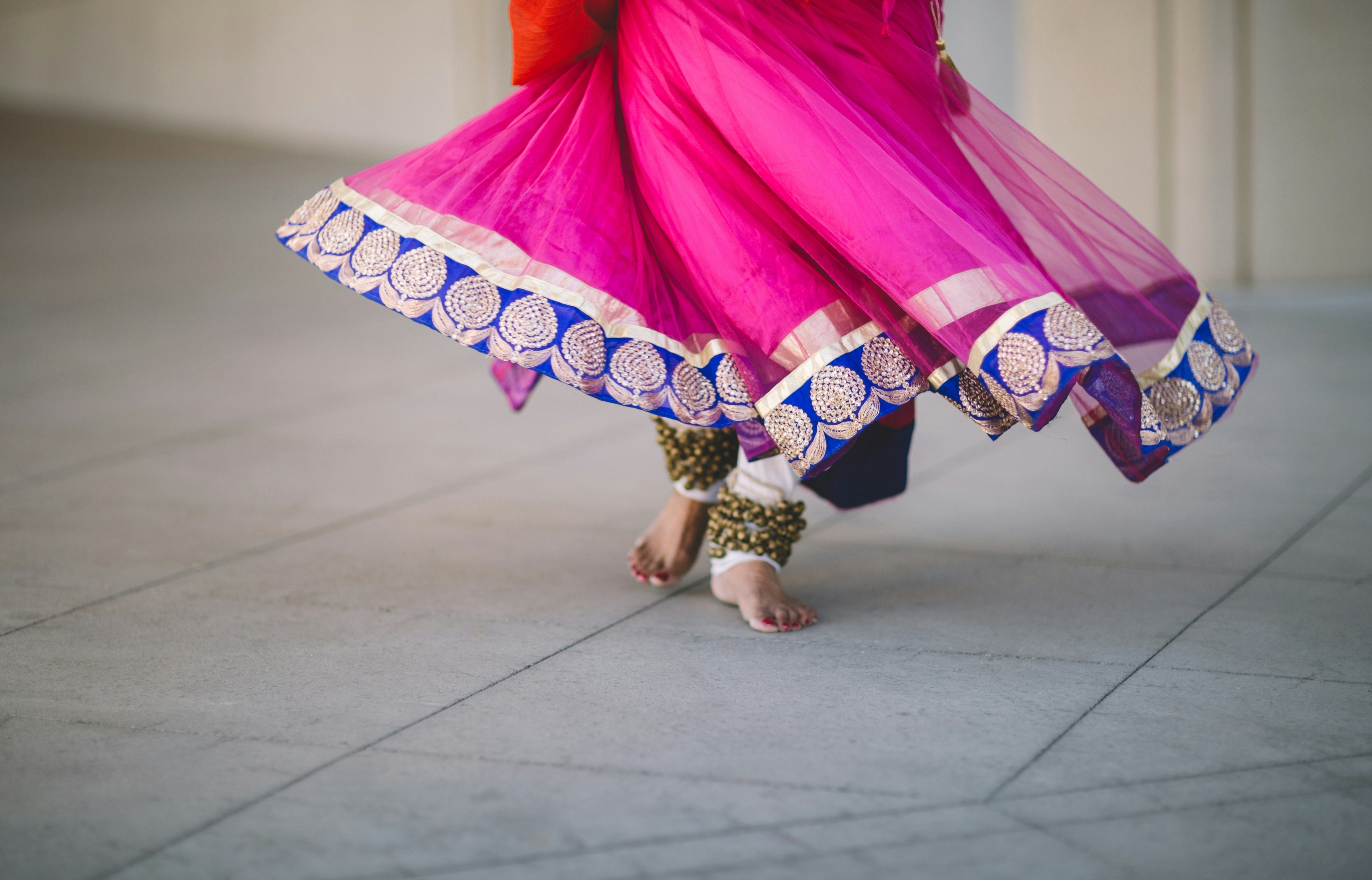 South Asian woman wearing a bright pink dress and their are bangles around her feet